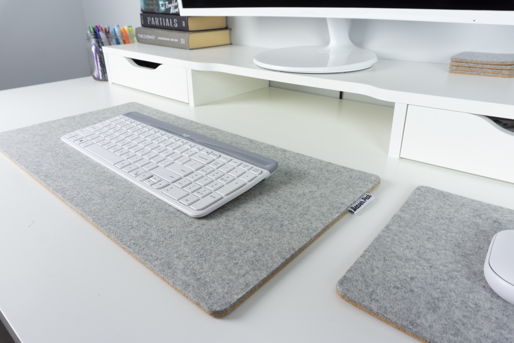 Wool felt and cork desk mat in grey with white keyboard next to matching grey wool mousepad with white mouse