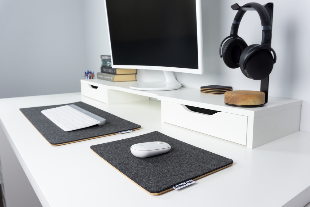 Black wool felt mouse pad next to black merino wool desk mat. Matching natural stained headphone stand as well, all on white desk