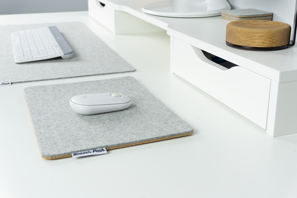 Grey merino wool felt mouse pad next to grey merino wool desk mat, all on white desk