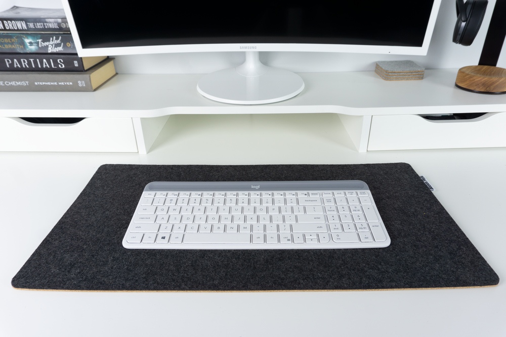 Black wool felt and cork desk mat with white keyboard on top