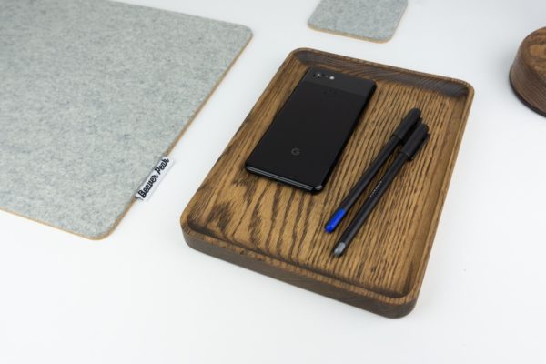 Wood accessory tray with pens and phone, next to grey desk mat