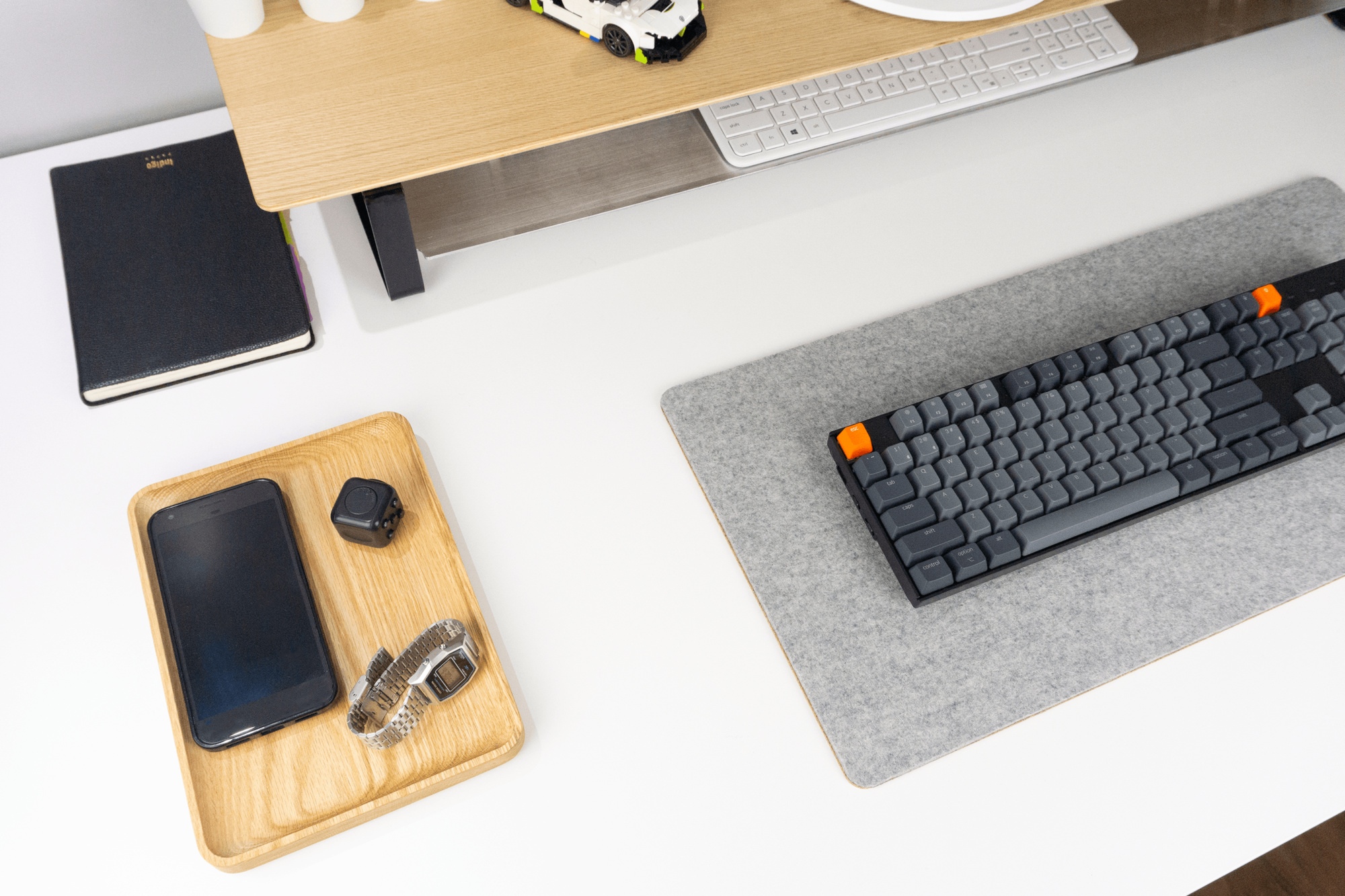 Oak desk tray next to grey wool felt desk mat and wooden desk shelf with storage.