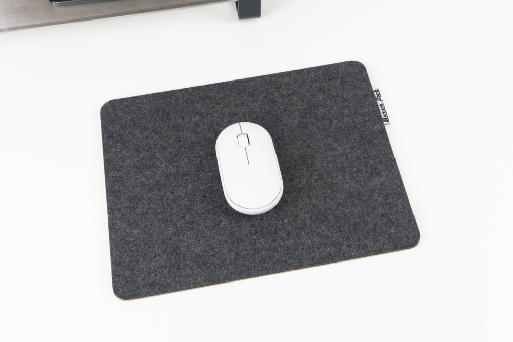 Black merino wool mouse pad with white mouse in middle, sitting on desk