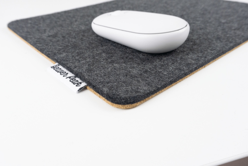 Close up of black wool felt mouse pad with white mouse.