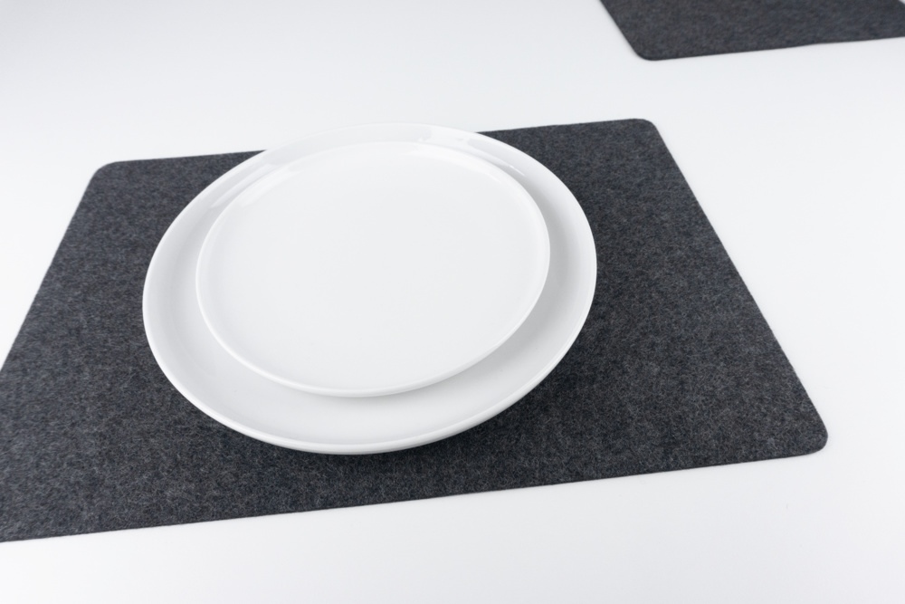 Black merino wool felt placemat set, shown with white plates