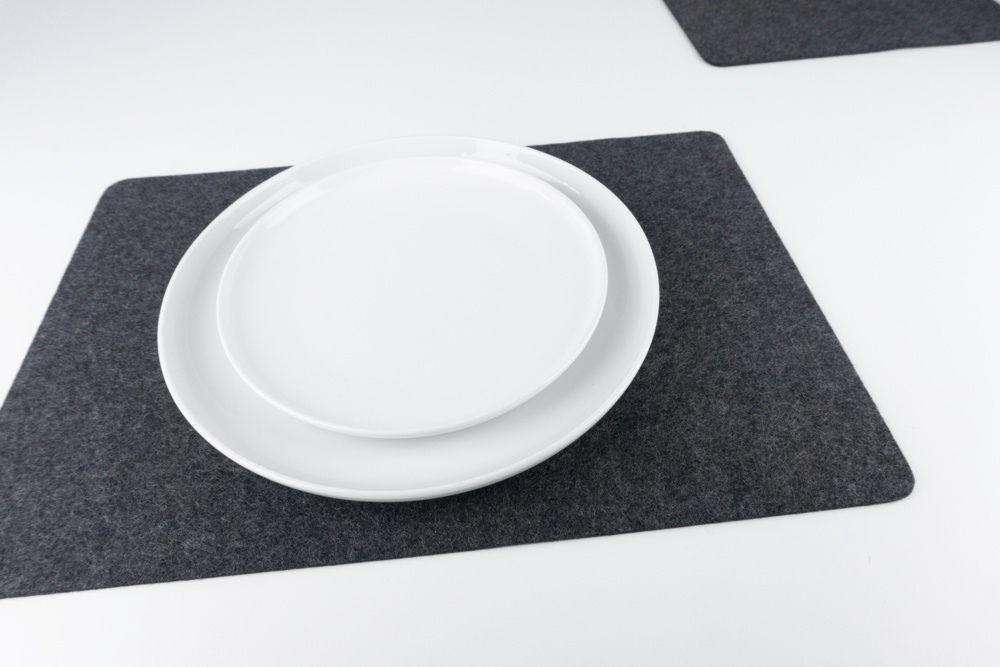 Black merino wool felt placemat set, shown with white plates.