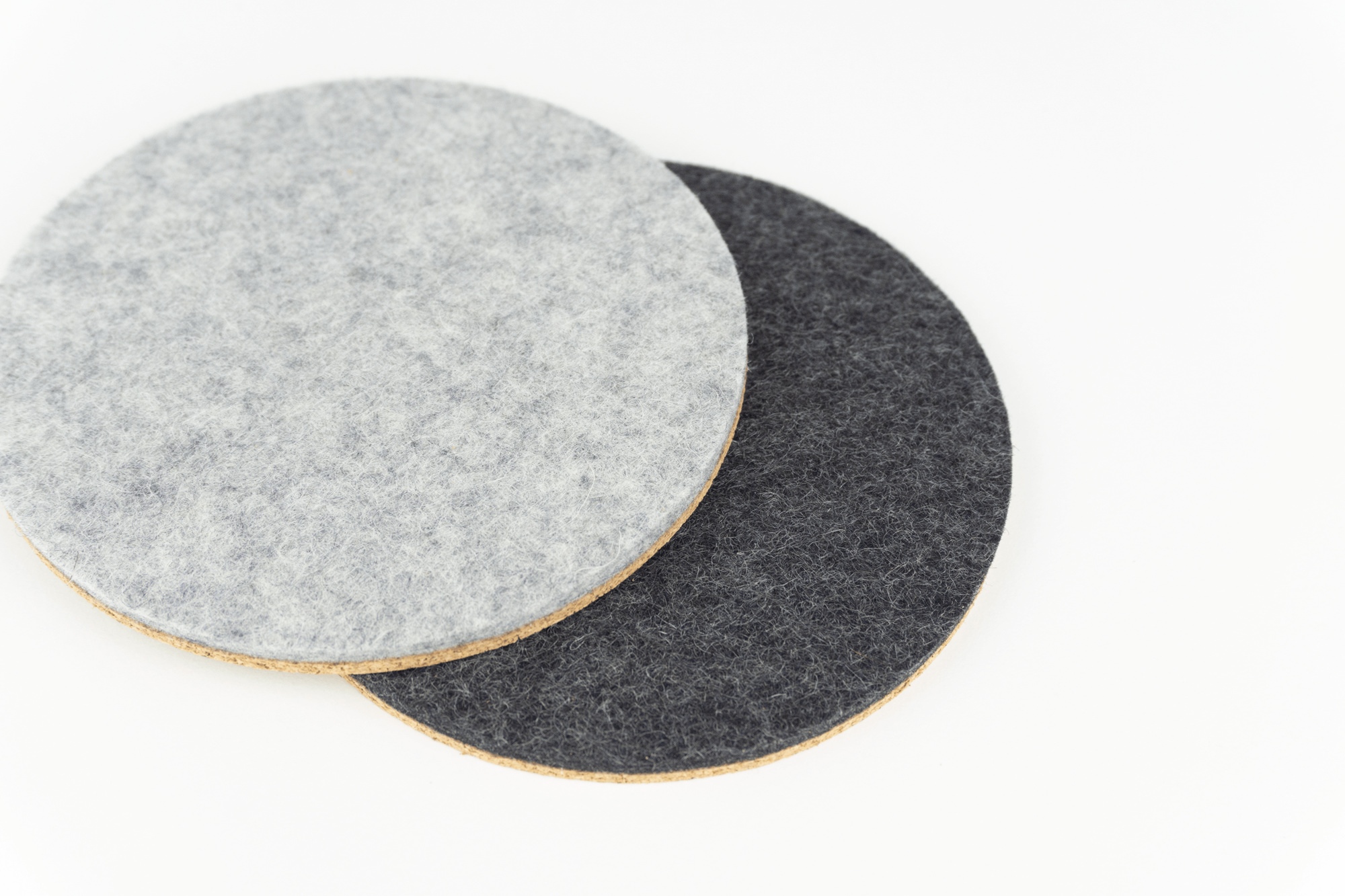Colour comparison of our light grey and black circle desk coasters, shown against a white coffee table.