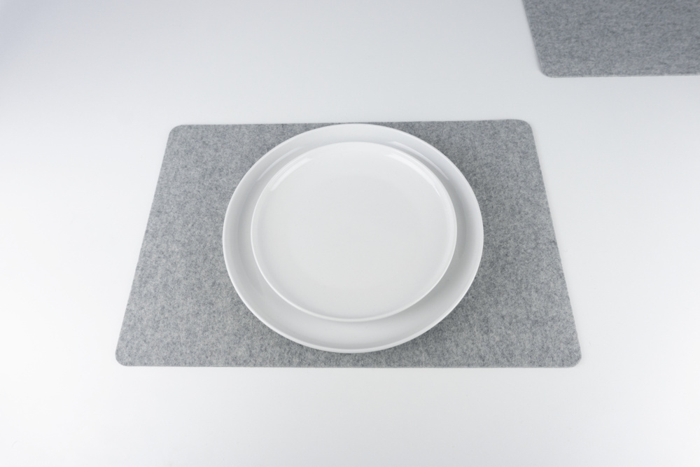 Grey merino wool felt placemat set, shown with white plates.