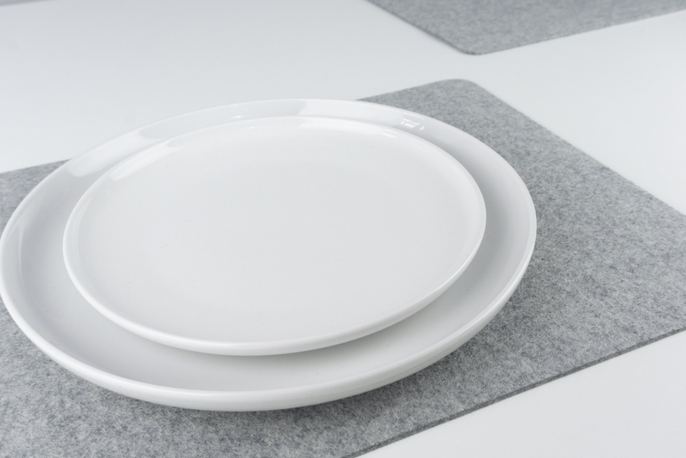 Closeup of Grey merino wool felt placemat set, shown with white plates