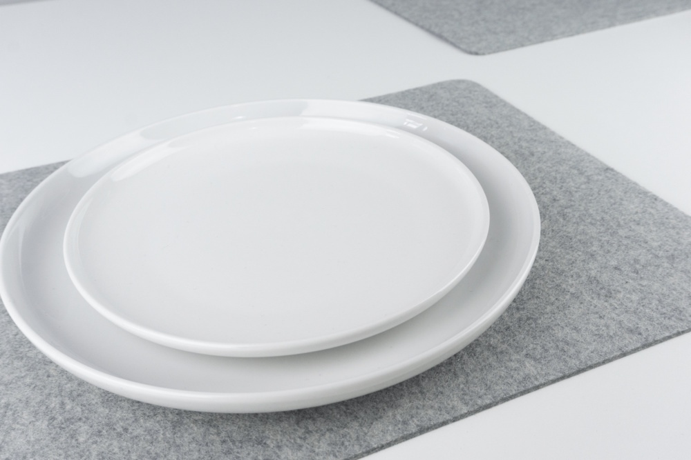 Closeup of Grey merino wool felt placemat set, shown with white plates.