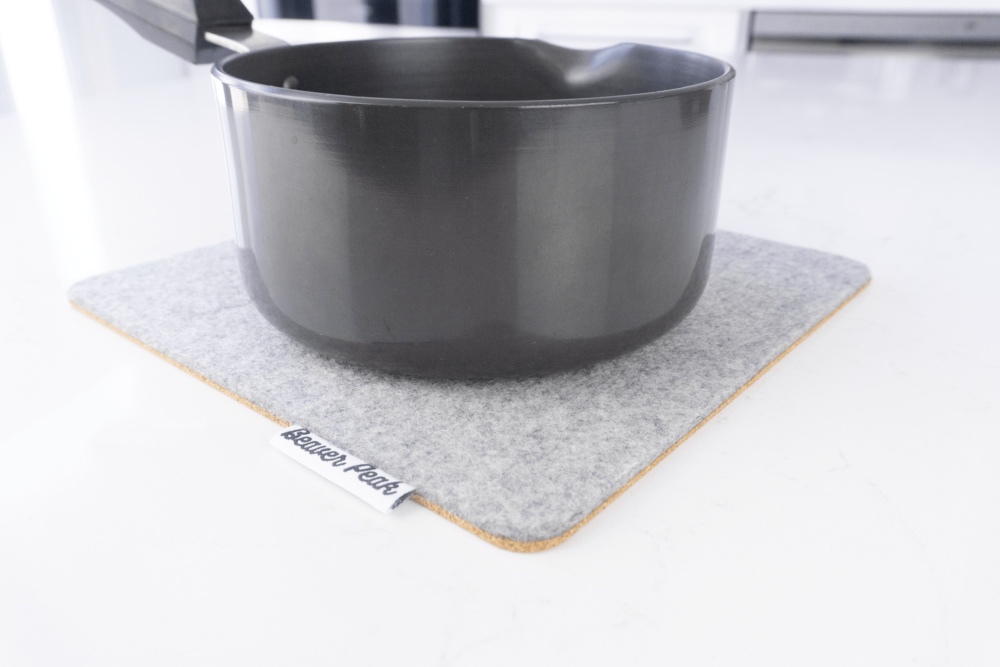 Grey merino wool felt trivet with black metal pot on top.