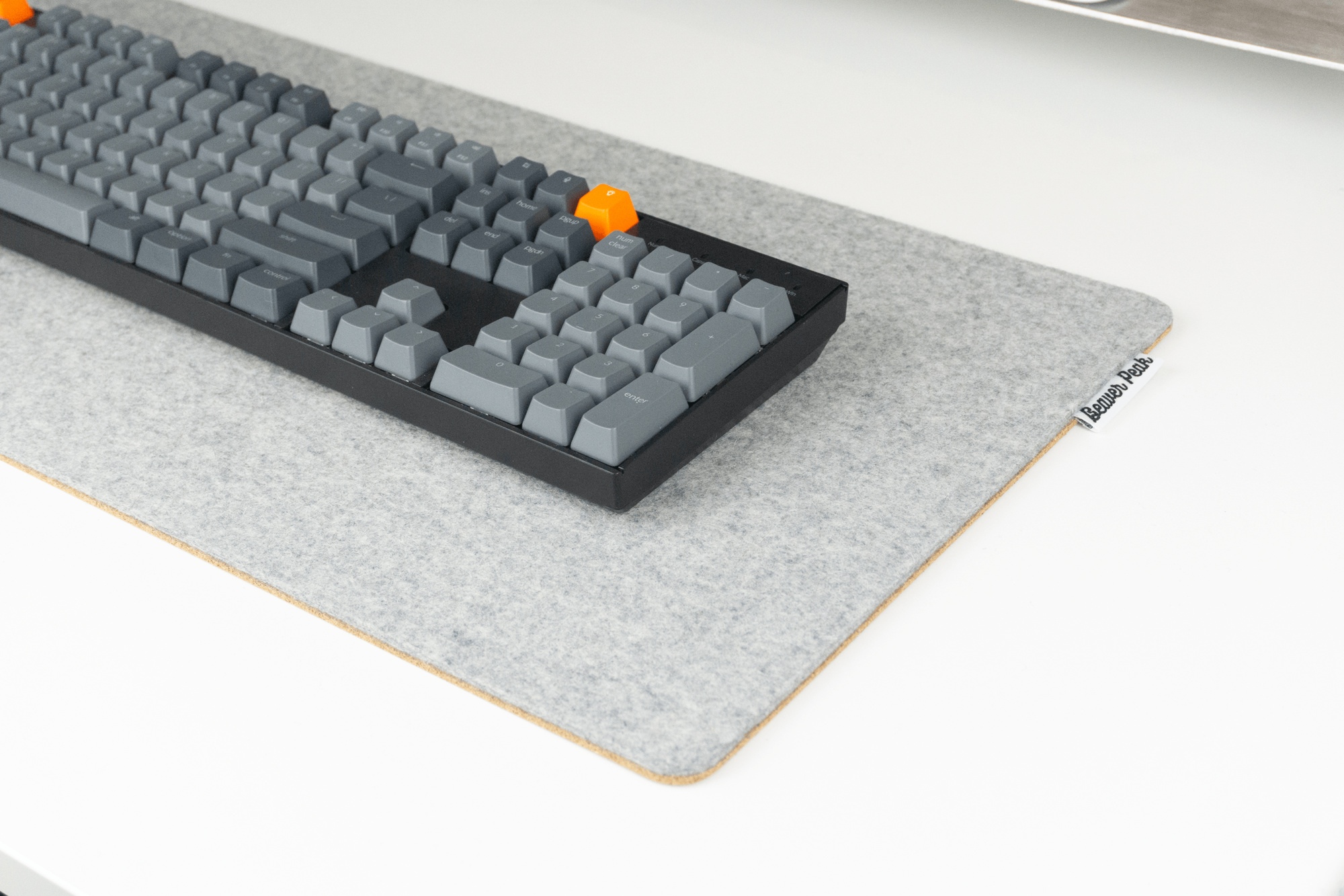 Grey merino wool felt and cork desk pad with BeaverPeak logo tag on the right side and a Keychron mechanical keyboard on top.