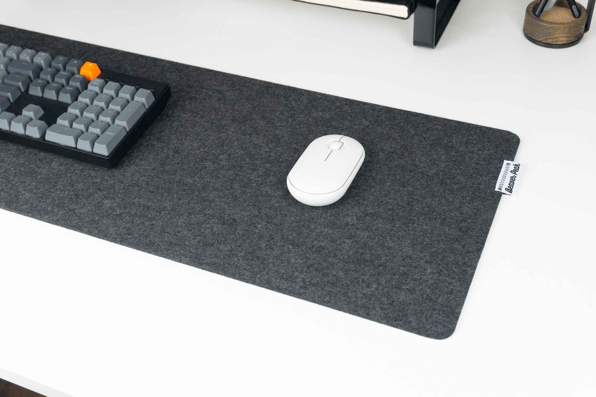 Black wool desk mat with white mouse and mechanical keyboard on top