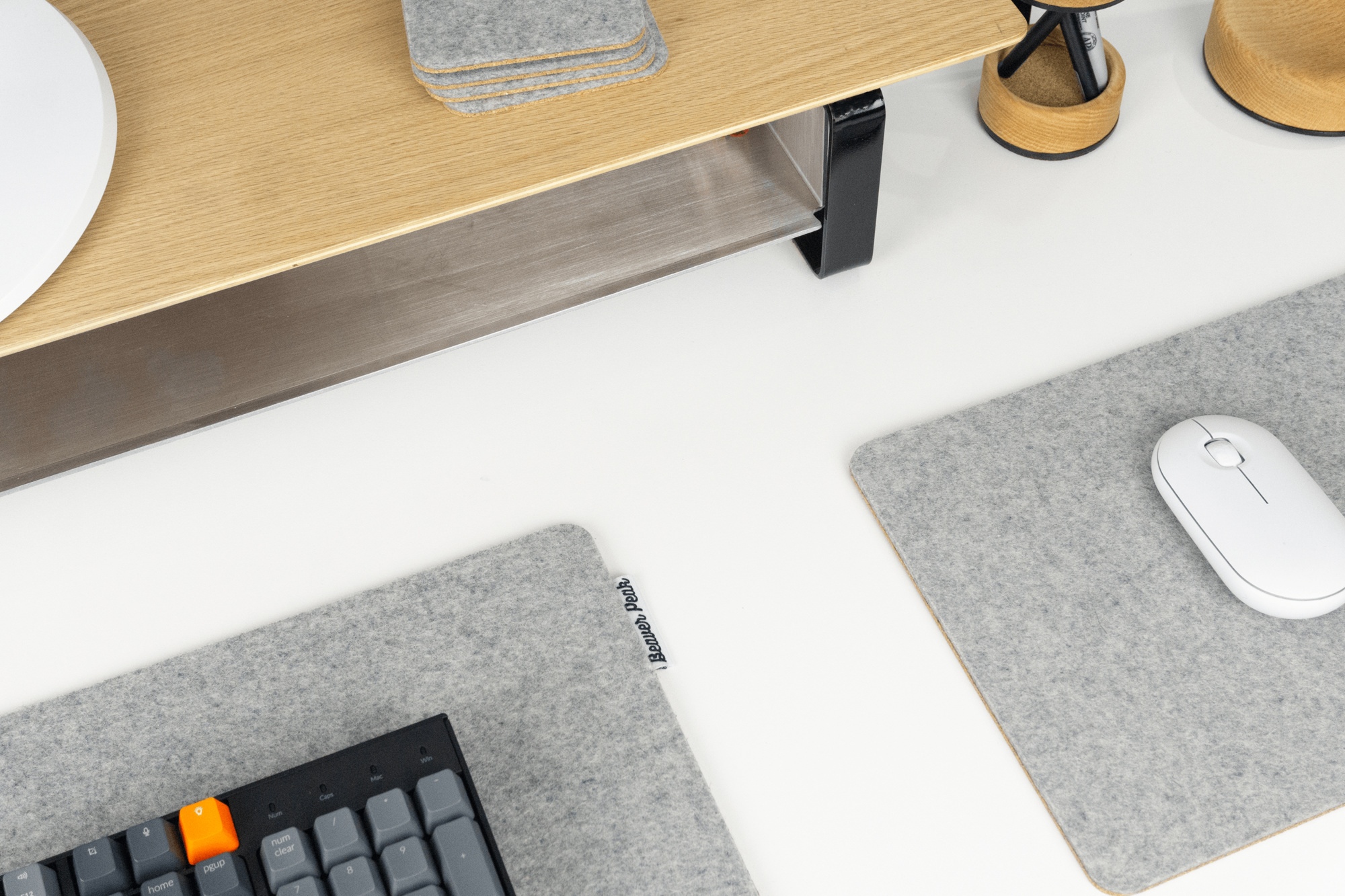 Grey wool desk pad next to matching grey mouse pad. With mechanical keyboard and white mouse.