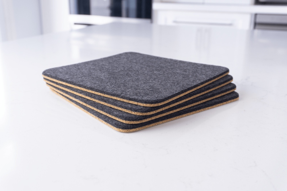 Set of 4 wool felt trivets in black merino wool, shown stacked.