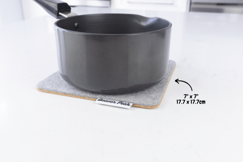 Grey merino wool felt trivet with black metal pot on top with dimensions showing: 7 x 7 inches, 17.7 x 17.7 inches.