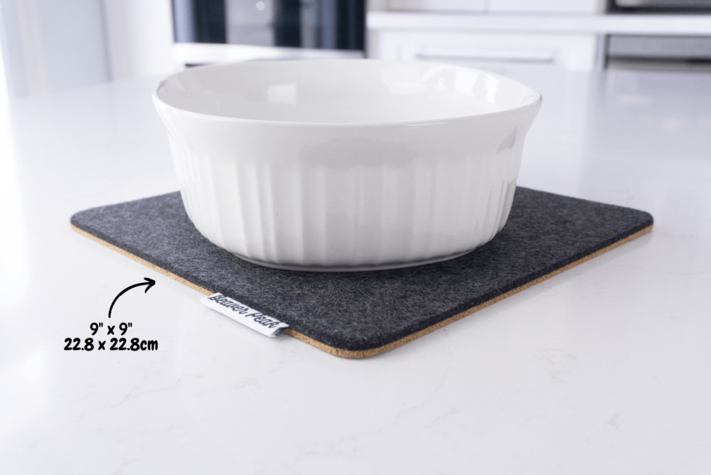 Black wool felt trivet with white ceramic pot on top, showing dimensions: 9 x 9 inches, 22.8 x 22.8 cm.