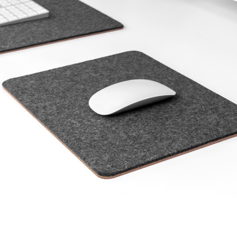 black mouse pad from shallow angle with white apple magic mouse on top and matching black desk mat in the background.